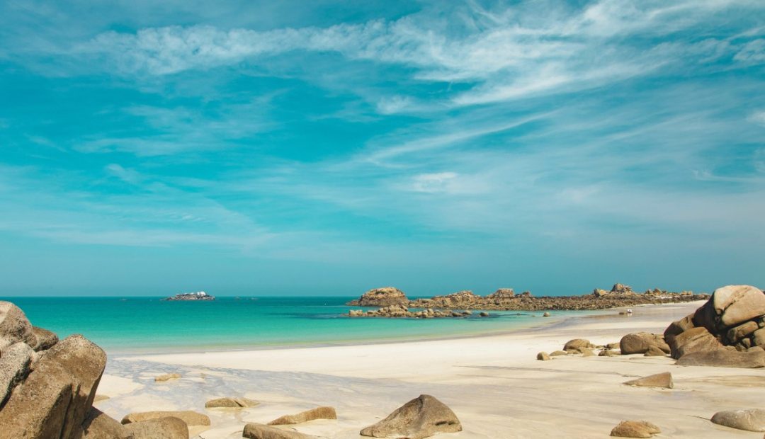 Plage de sable bordee de rochers et de mer turquoise sur la cote du Finistere