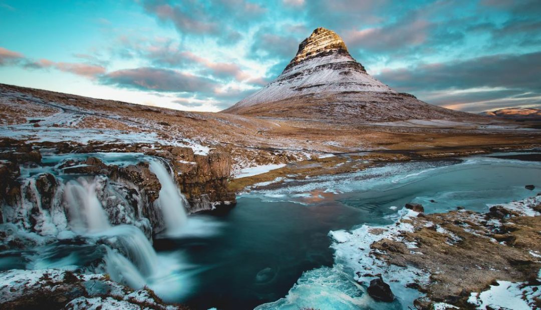 Montagne Kirkjufell enneigee et sa cascade au crepuscule en Islande