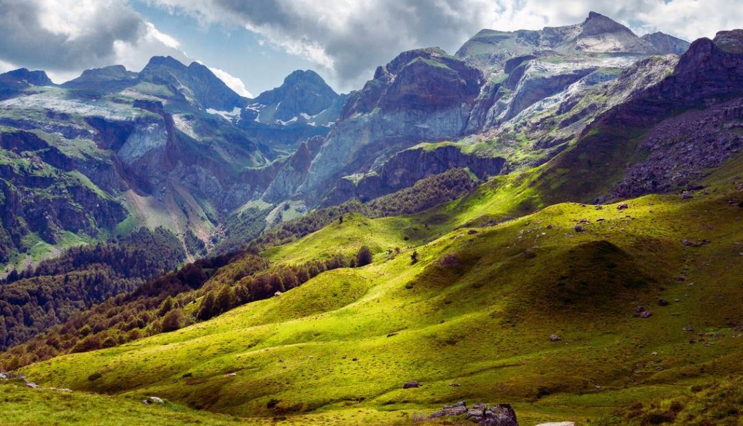 Vallée verdoyante des Pyrénées françaises avec prairies alpines et sommets rocheux