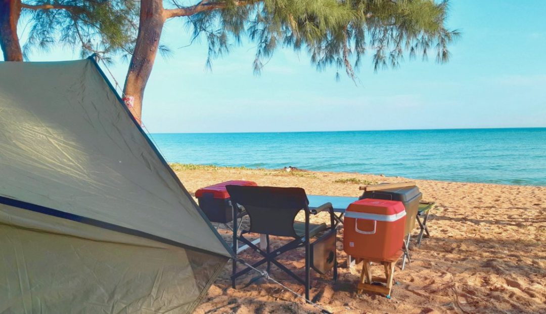 Tente de camping installée sur une plage de sable au bord de la mer turquoise